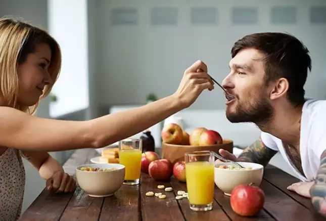 Una mujer alimenta a un hombre con nueces para aumentar la potencia. 
